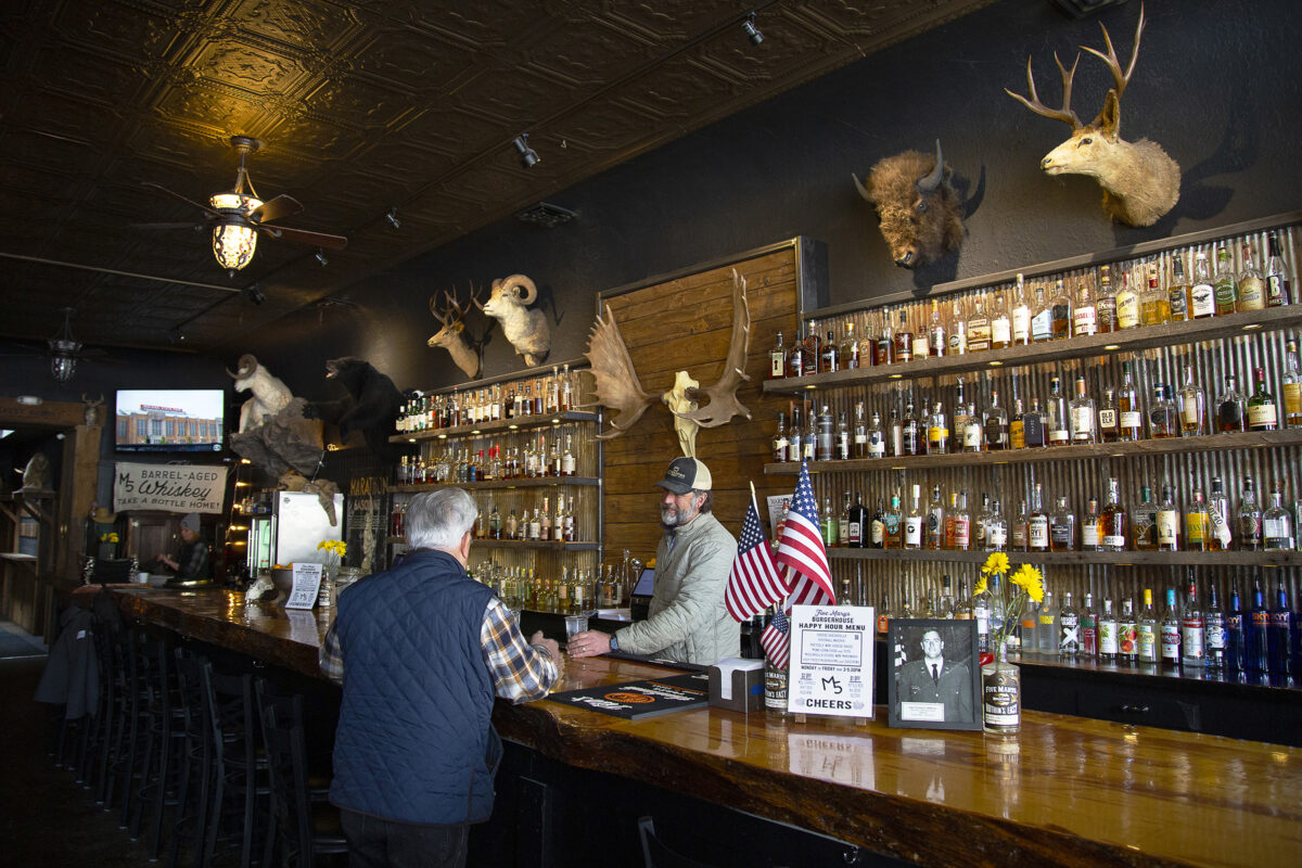 Bartender serves a lone customer at a rustic bar owned by Five Marys Farms in Fort Jones, California.