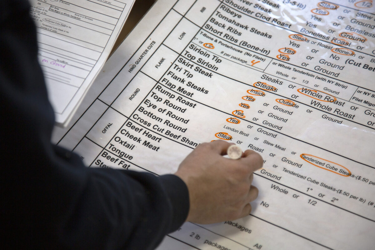 Butcher filling out a beef cut sheet used for meat processing production.