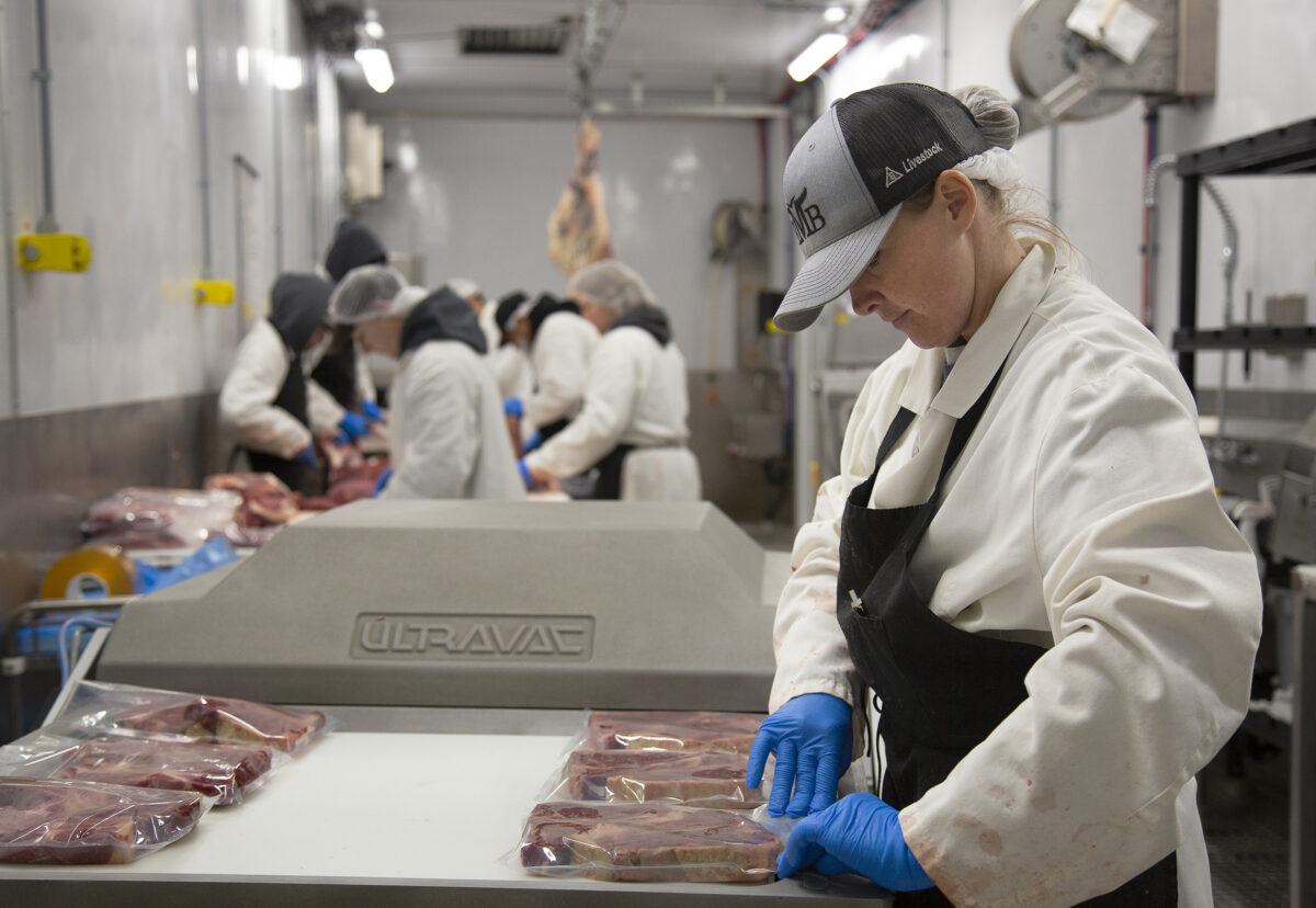 A butcher seals steaks in vacuum packages inside the Cut and Wrap Module of a Friesla Processing System.