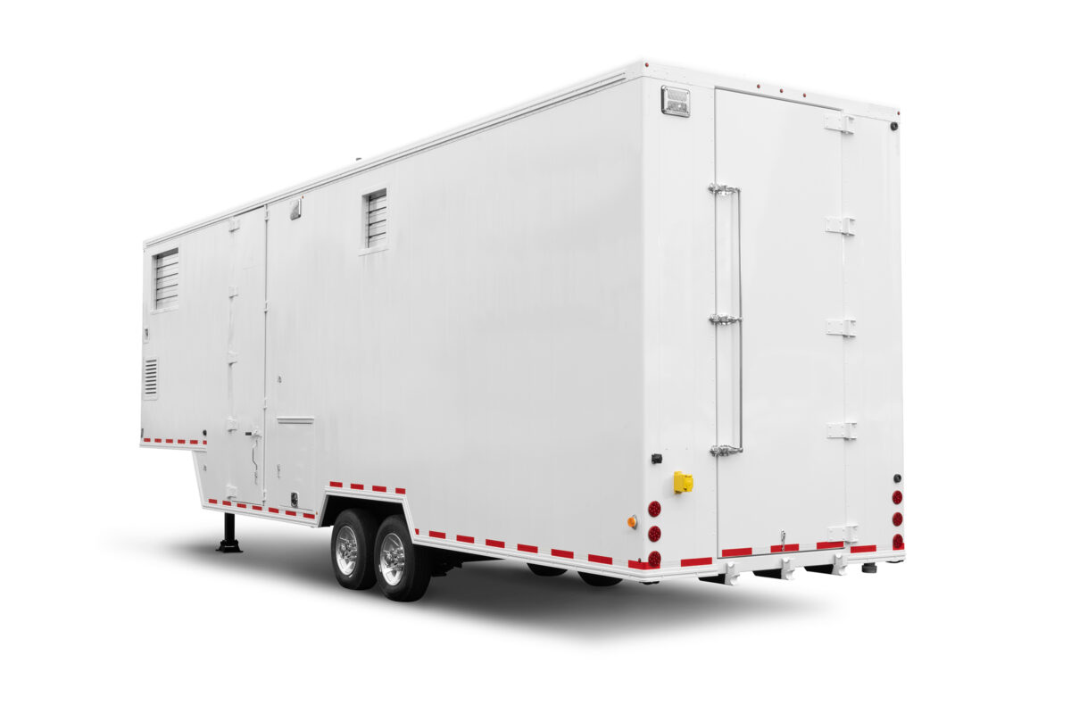 A rear view of a white, 38-foot-long Friesla Mobile Meat Harvest Unit used for on-site meat processing.