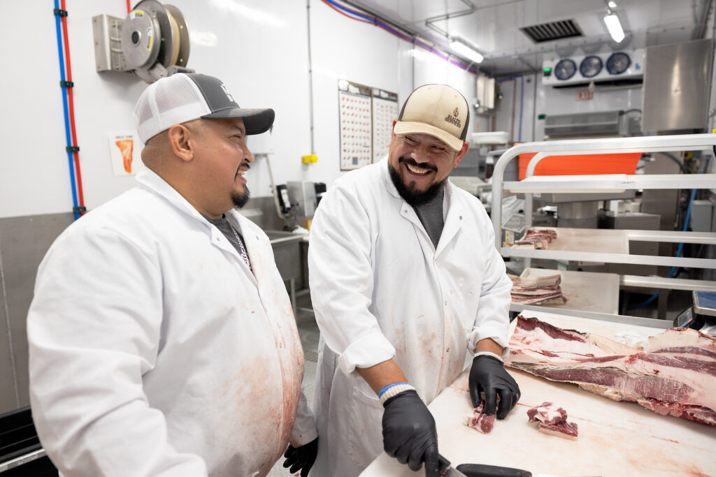 Smiling MTX Beef butchers fabricate and breakdown beef carcasses on polytop cutting tables in their Friesla Cut & Package Module.